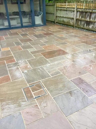 Wet patio with a variety of stone tiles in a patchwork pattern.