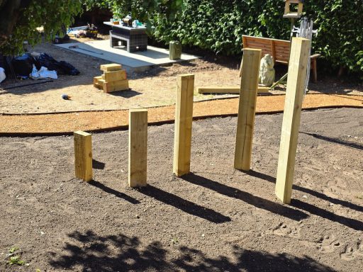 Several oak sleepers of varying heights arranged in a garden setting.