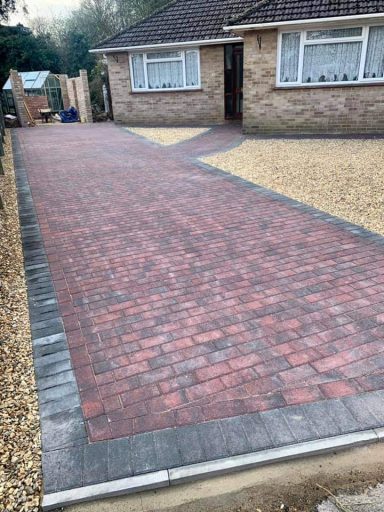 Block-paved driveway with a mix of red and grey bricks leading to a house.