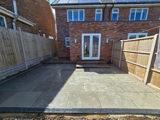 Paved outdoor space with a patio door and surrounding wooden fences.