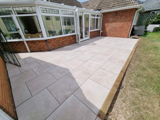 Patio area with large stone tiles and grass, adjacent to a conservatory.